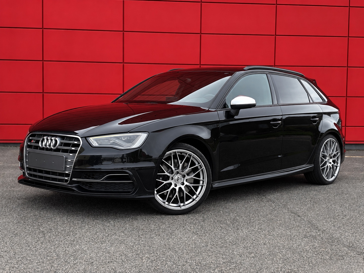 Černé Audi S3 Sportback před červenou stěnou